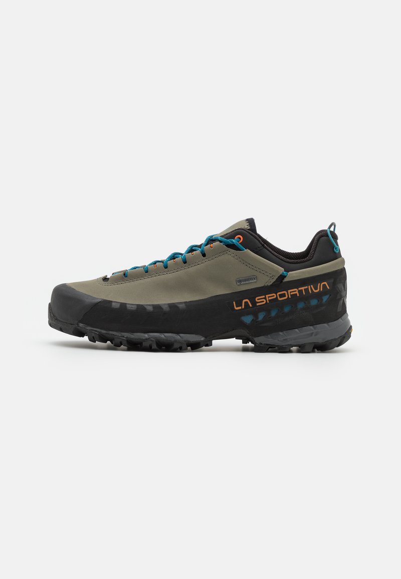 Męskie buty trekkingowe w kolorze oliwkowym, z czarnym gumowym czubkiem, niebieskimi sznurówkami i pomarańczowymi akcentami. Teksturowana podeszwa zaprojektowana do zapewnienia przyczepności.