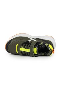 Zapatilla con parte superior en verde oliva y negro, acentuada con detalles amarillos y forro de camuflaje. Suela blanca gruesa con detalles en naranja. Correa ajustable.