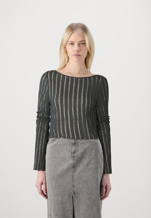 Sort langærmet top med lodrette beige striber, rund halsudskæring og en afslappet pasform. Stylet med en grå denimnederdel med en slids foran.