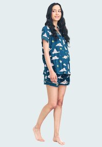 Conjunto de pijama azul marino que incluye una camiseta de manga corta y pantalones cortos. Decorado con nubes blancas, estrellas y animales juguetones. Tela suave y corte relajado.