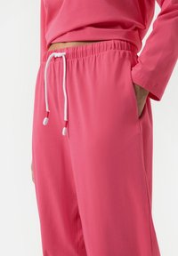 Roze katoenen joggingsbroek met een elastische tailleband en witte drawstring. Voorzien van zijzakken en een zachte, gladde textuur.