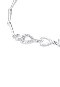 Bracciale d'argento con charm a forma di cuore collegati, uno decorato con piccole pietre luccicanti, su uno sfondo bianco.