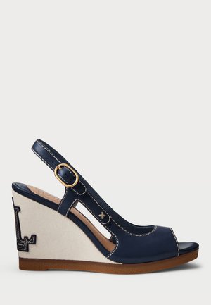 Marineblauwe leren sleehak sandaal met beige stoffen hak, open teen, slingback bandje, gouden gesp en decoratieve witte stiksels.