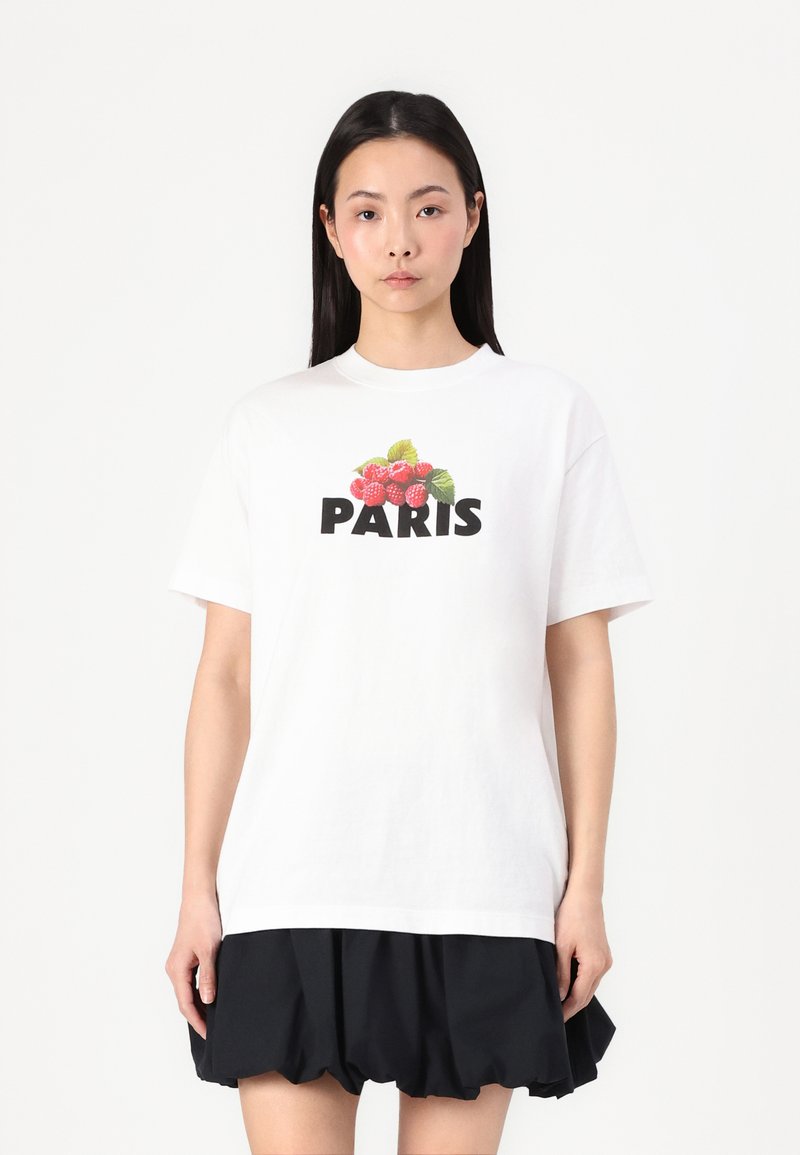 T-shirt en coton blanc avec un graphique coloré de framboise et "PARIS" en lettres noires en gras, avec une coupe décontractée et des manches courtes.