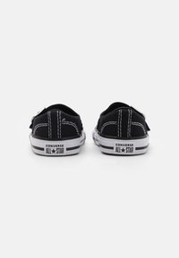 Zapatillas Converse All Star negras de lona, diseño de corte bajo, suelas de goma blanca, costuras en blanco contrastantes y ojales plateados.