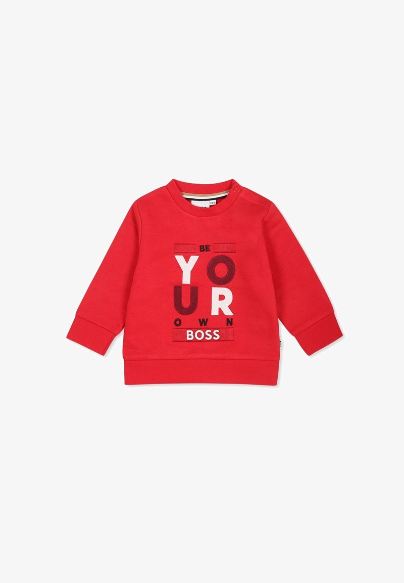 Sweat-shirt rouge à manches longues pour tout-petit avec boutons-pression à l'épaule, portant le texte « Sois ton propre patron » en lettres mélangées blanches et rouge foncé.