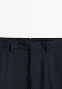 Pantalon bleu marine foncé avec une texture de tissu lisse, doté d'une fermeture à bouton, de passants de ceinture et d'un motif à carreaux subtil sur toute la surface.