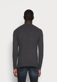 Maglione grigio scuro realizzato in morbido tessuto a maglia, con scollatura tonda e maniche lunghe. Progettato con orlo e polsini a coste.