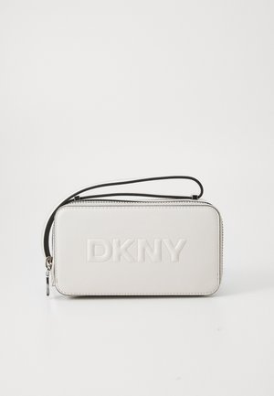 Balts ādas maisiņš ar izsistām "DKNY" logo, melnu rāvējslēdzēju un siksnu. Kompaktera taisnstūrveida forma ar gludu tekstūru.