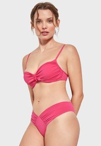 Conjunto de bikini rosa que incluye un top anudado con tirantes ajustables y una parte de arriba de talle alto con detalles fruncidos. Tejido de textura suave.