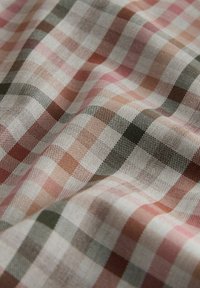 Tessuto strutturato con un motivo a quadri multicolore in tonalità di rosa, marrone e verde, con un aspetto morbido e intrecciato.