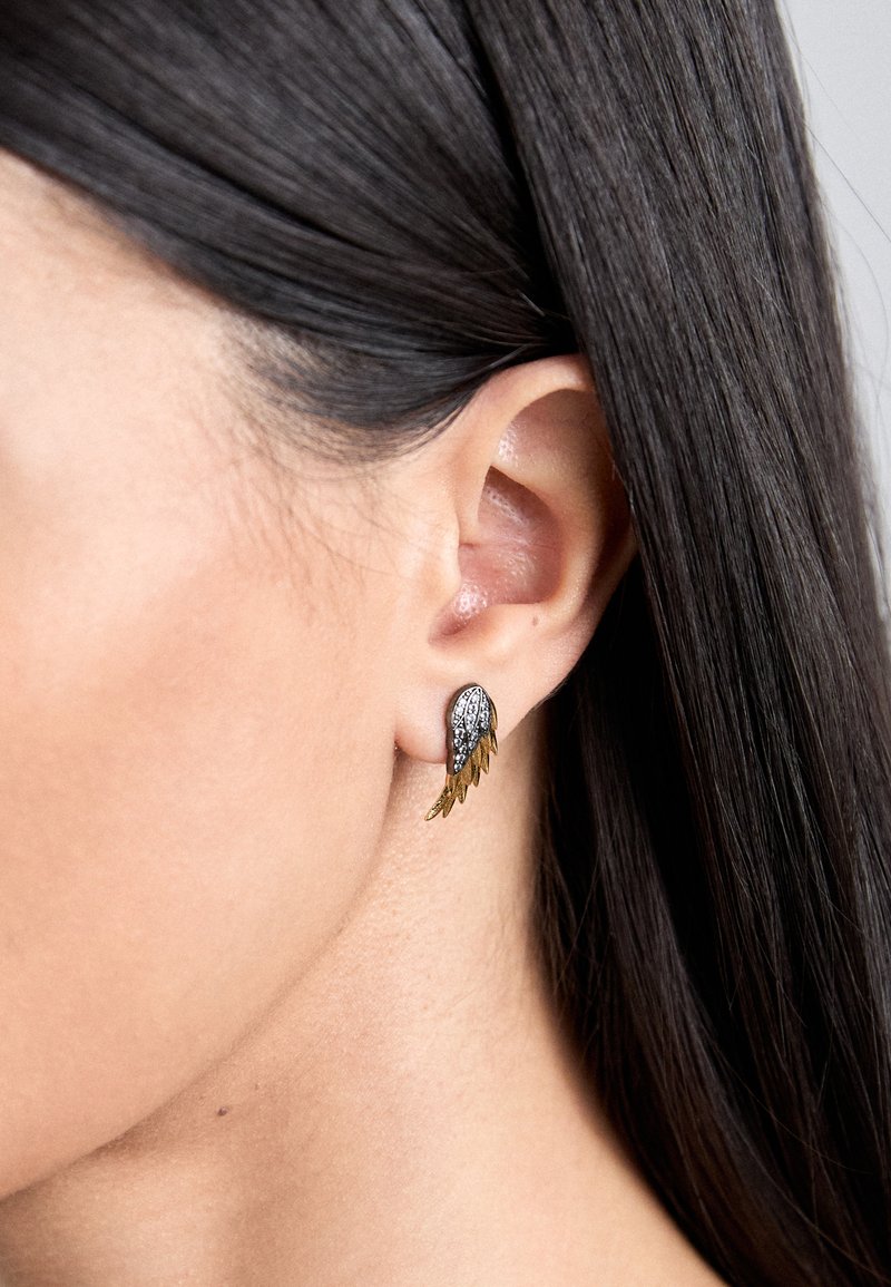 Silver and gold wing-shaped stud earring with intricate detailing, featuring a textured surface and a small rhinestone accent.