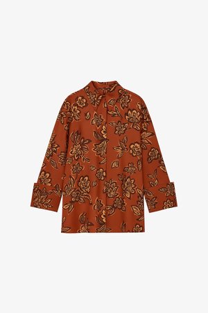 Blusa color óxido con mangas largas, estampado floral en negro y amarillo, y parte frontal sin botones, con un ajuste relajado y cuello.