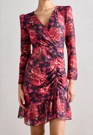 Vestido mini con mangas largas y fruncido, con estampado floral rojo y rosa sobre fondo azul marino y bajo con volantes.