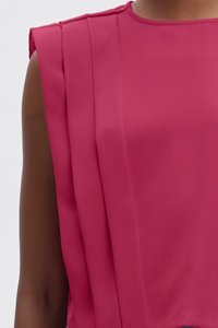 Haut sans manches fuchsia avec des détails plissés, possédant une texture lisse et un col rond. Le tissu semble léger et fluide.