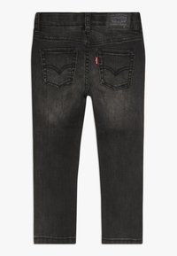 Jeans de mezclilla negra con un diseño ajustado, que presentan un estilo clásico de bolsillo trasero y un sutil desgaste. Incluye un parche con el logo de Levi's en la cinturilla.