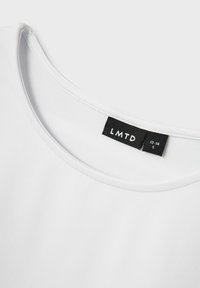 Baltos medvilnės marškinėliai su apvaliu kaklu. Su juodu žymekliu „LMTD“ ir dydžio informacija, sukurtas su lygiu, vientisu paviršiumi.