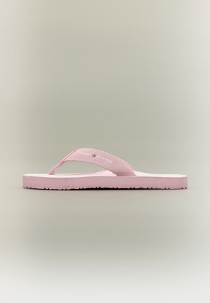 Infradito a righe rosa con cinturino in tessuto mostrante il logo "Tommy Hilfiger" su sfondo grigio neutro, vista laterale.