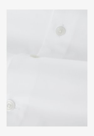 Biely odevný materiál so dvoma viditeľnými bielymi okrúhlymi gombíkmi prišitými na hladkom povrchu.