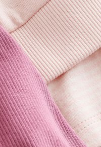 Bomullstyg i ljusrosa och mauve, med ränder och släta texturer, synliga sömmar och en mjuk yta.