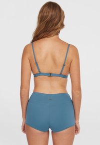 Ensemble de maillots de bain bleu avec bretelles réglables et bas taille haute en tissu lisse et extensible, conçu pour le confort et un bon ajustement.