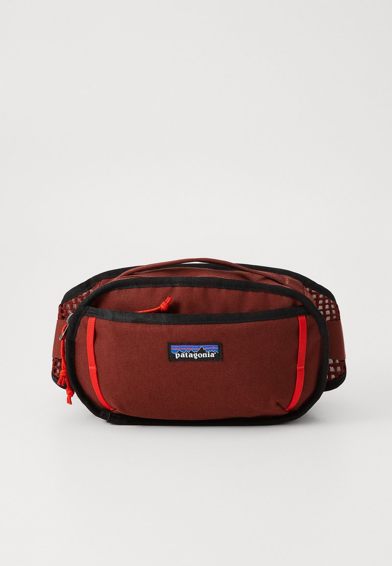 Marsupio Patagonia, tessuto rosso scuro con accenti neri, pannello in rete sul lato, tirazip rossi staccabili e patch del logo sul fronte.