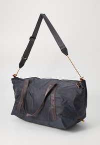 Große schwarze Nylon-Tasche mit zwei Griffen, einem verstellbaren Gurt, roten Akzenten und einem Reißverschluss. Strukturiertes Oberflächenmaterial mit strapazierfähiger Naht.