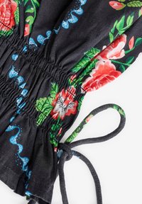 Îmbrăcăminte florală neagră cu elastic strâns la talie, având trandafiri roșii și frunze verzi, accentuată de modele ondulate albastre și curele.