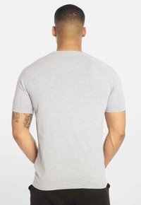 Grå kortærmet t-shirt med rund hals. Fremstillet af et glat stof, med raglanærmer og en afslappet pasform. Ingen synlige mønstre.