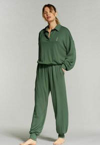 Set di abbigliamento loungewear verde caratterizzato da una camicia con colletto, col bottone e dettagli ricamati, abbinata a pantaloni a gamba larga e svasati.