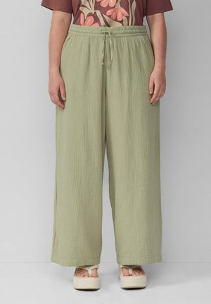 Pantalons larges vert clair avec une taille élastique et un cordon de serrage. Tissu texturé, semblant doux, assortis avec un haut floral à motifs.