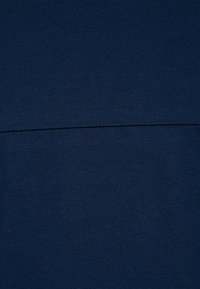 Mörkblå tyg med en slät yta, med en horisontell söm mitt på, vilket indikerar en enkel och välpassande design.