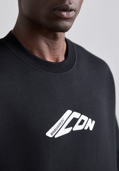 Felpa nera con collo rotondo, caratterizzata da una grande grafica bianca "ICON" e il testo "DSQUARED2". Il tessuto appare liscio con una vestibilità rilassata.