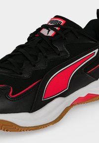 Chaussure de sport Puma noire et rouge avec une semelle intermédiaire blanche, une semelle extérieure en gomme, des lacets noirs et le logo Puma sur la languette et le panneau latéral.