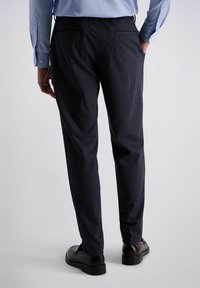 Donkerblauwe, gestructureerde broek met een tailormade pasvorm. Heeft twee achterzakken en wordt gedragen met zwarte schoenen. Weergave van de achterkant.
