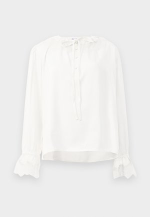 White long-sleeve blouse made of smooth fabric, featuring a round neckline, button closure, and lace-trimmed cuffs. Adjusts with a tie at the neck.