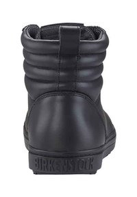 Schwarze Leder-Stiefeletten mit gepolstertem Kragen, mit Steppnähten und einer strukturierten Sohle. Der Markenname ist auf der Ferse eingeprägt.