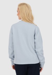 Felpa azzurra con maniche lunghe, collo a giro e una texture liscia. Presenta polsini e orlo a costine per una vestibilità sicura.