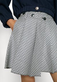 Gonna a quadri grigia e blu navy, con un design svasato, due tasche frontali e chiusura anteriore con doppio bottone e bottoni in contrasto.
