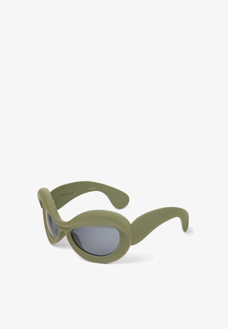 Vihreät, teksturoidut aurinkolasit ylisuurilla, munan muotoisilla kehyksillä ja tummilla linsseillä. Sivut ovat sileäpintaiset, sulautuen kehysten muotoiluun.