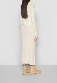 Krämfärgad ribbad stickad tröja och midikjol, kompletterad med beiga klumpiga stövlar med dragkedja på sidan och texturerad sula.