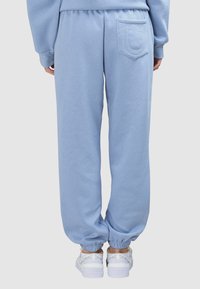 Hellblaue Jogginghose aus weichem Stoff, mit einer Gesäßtasche mit Ziernähten und elastischen Bündchen an den Knöcheln.