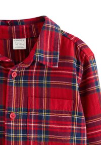 Rød, blå og gul ternet skjorte med lange ærmer, krave og brystlomme med røde knapper, størrelsesmærke til børn i alderen 4-5 år.