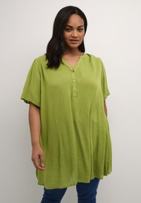 Tunic verde a maniche corte in tessuto leggero e testurizzato con colletto rotondo e chiusura con bottoni. Vestibilità ampia con orlo curvo.