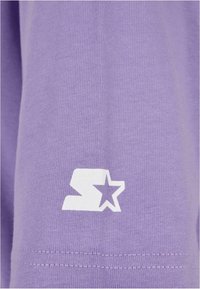Purple sweatshirt featuring a smooth texture and a white logo design with an "S" and star on the sleeve. Simple and modern aesthetic.