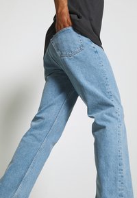 Jeans de mezclilla azul claro con corte recto, que presentan un bolsillo trasero, costuras sutiles y un acabado texturizado.