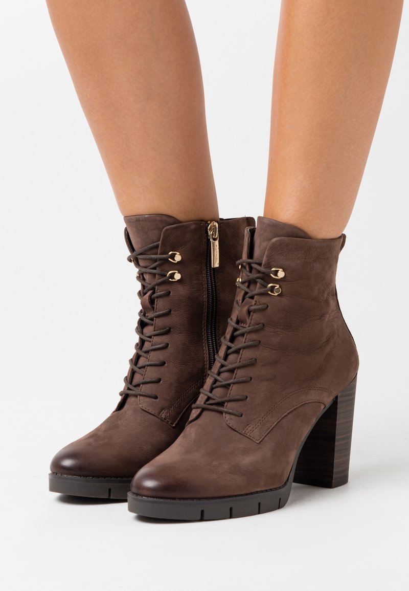 Braune Leder-Stiefeletten mit strukturiertem Finish, vorderer Schnürung, Reißverschluss und einem klobigen Absatz. Mit Hardware-Akzenten in Gold.