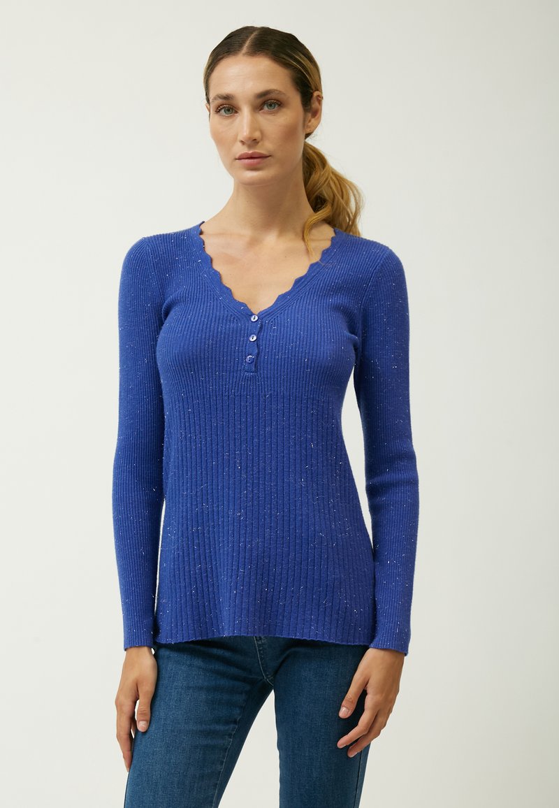 Maglione blu a coste con scollatura a V ondulata, maniche lunghe e quattro bottoni decorativi. Il tessuto presenta una texture screziata per un tocco di originalità.