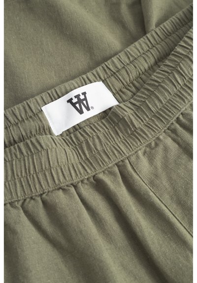 Buzunar de talie dintr-un material ușor, de culoare verde măsliniu, cu elastic gathered. Dispune de un eticheta albă cu un logo negru în centru. Textură netedă.