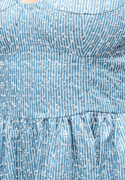 Μπλε-λευκό ριγέ ύφασμα με ασημένιες παγιέτες σε γεωμετρικά σχέδια σε μαζεμένο, υφασμάτινο υλικό με υφή.